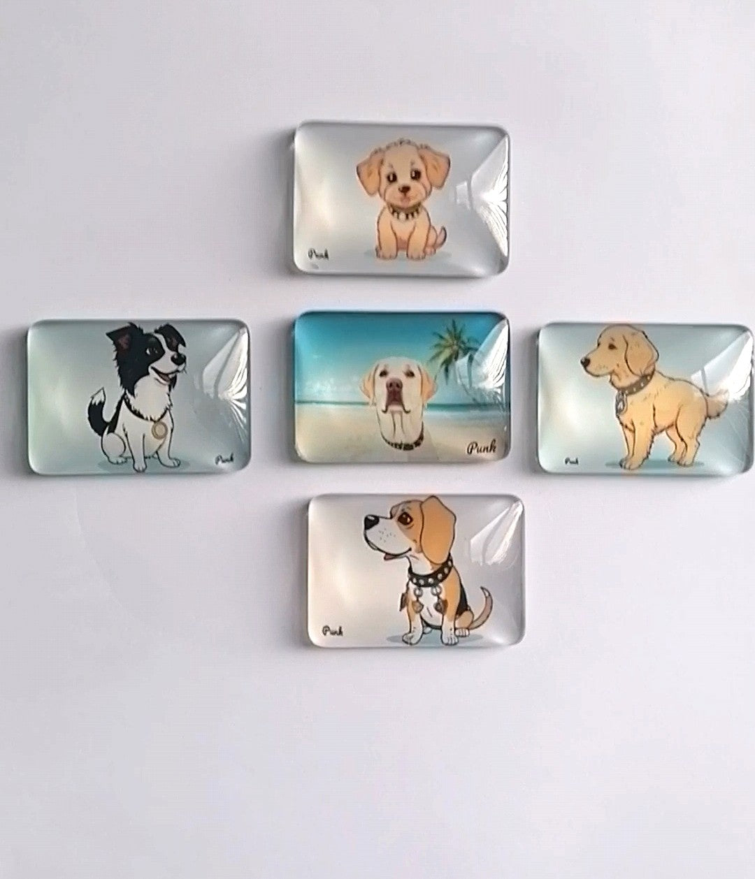 Five rectangular crystal glass fridge magnets on fridge featuring cartoon illustrations of different dog breeds, arranged on a plain white background.